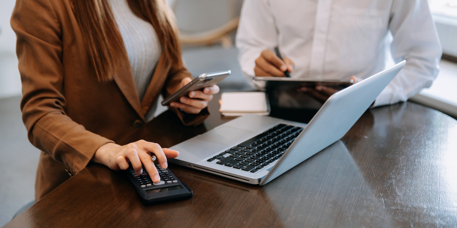 Business documents on office table with smart phone and calculator digital tablet and graph business with social network diagram and two colleagues discussing data working in the office